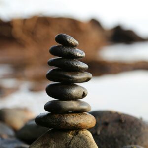 A stack of smooth stones artfully balanced by a waterside, evoking tranquility and zen.